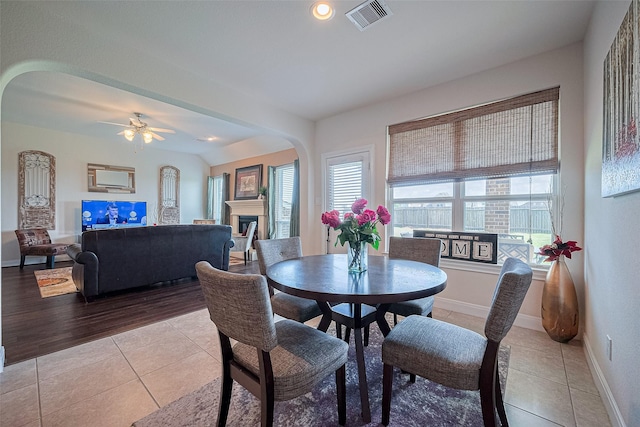 20322 Fossil Valley Ln, Cypress, TX 77433 - dining space with arched walkways, light tile patterned flooring, a fireplace, ceiling fan, and recessed lighting