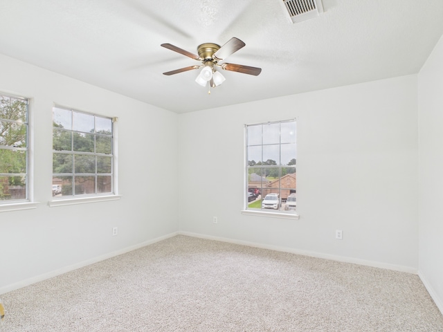 carpeted empty room featuring visible vents, baseboards, and ceiling fan