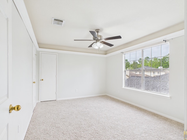 unfurnished room with a ceiling fan, crown molding, carpet floors, baseboards, and visible vents
