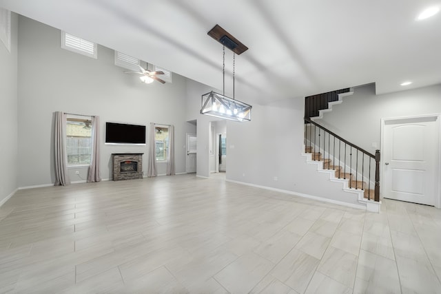 18203 Octavio Frias Trl, Atascocita, TX 77044 - unfurnished living room featuring stairs, a ceiling fan, a high ceiling, baseboards, and a fireplace