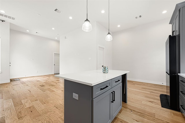 kitchen featuring gray cabinets, light countertops, visible vents, and freestanding refrigerator