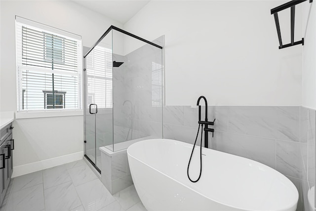 bathroom featuring a stall shower, a freestanding tub, vanity, tile walls, and marble finish floor