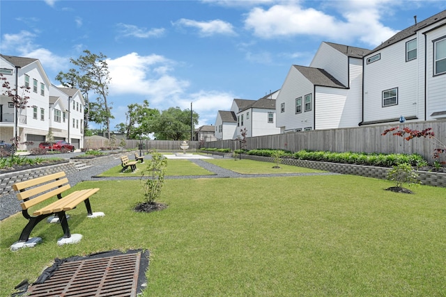 view of home's community with fence, a yard, and a residential view