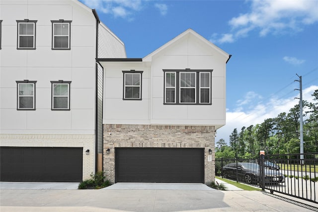 view of front of property featuring brick siding, an attached garage, concrete driveway, and fence