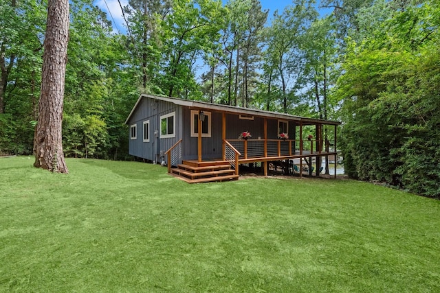 back of property featuring board and batten siding, a lawn, and a deck