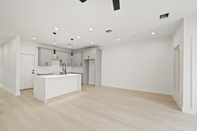 8131 Woodward St, Houston, TX 77051 - kitchen featuring gray cabinetry, ceiling fan, an island with sink, recessed lighting, and light wood-style floors