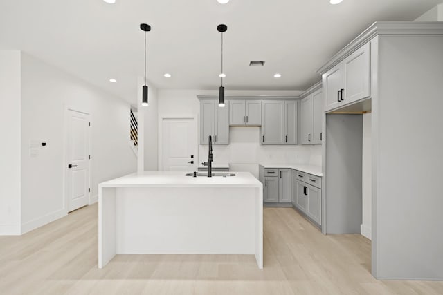 8131 Woodward St, Houston, TX 77051 - kitchen with gray cabinetry, light wood finished floors, recessed lighting, an island with sink, and decorative light fixtures
