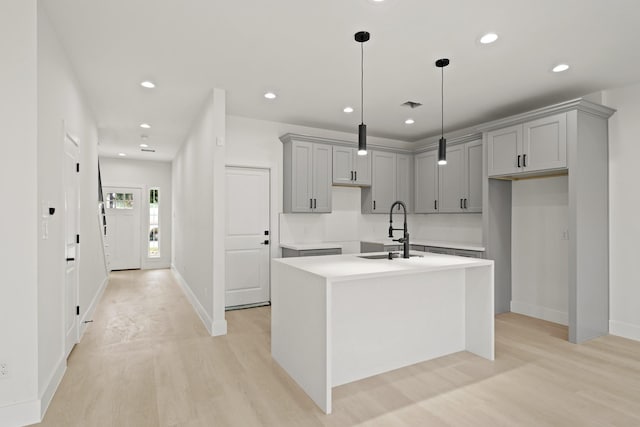 8131 Woodward St, Houston, TX 77051 - kitchen with gray cabinets, light wood-style flooring, an island with sink, recessed lighting, and hanging light fixtures