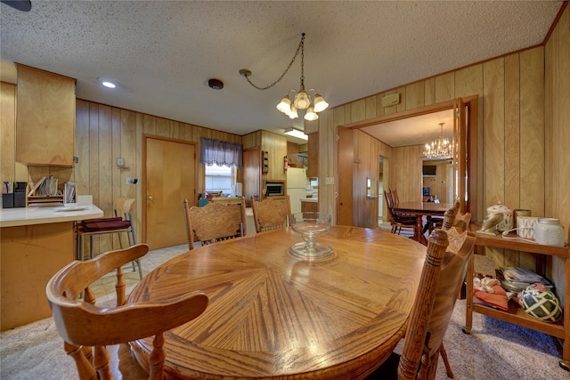 dining area with wood walls, a textured ceiling, and a notable chandelier