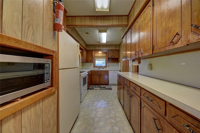 kitchen with light floors, light countertops, brown cabinetry, and white appliances