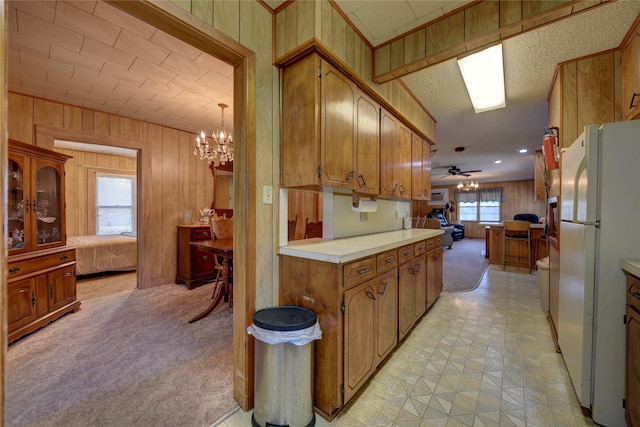 kitchen featuring brown cabinets, open floor plan, light countertops, light colored carpet, and freestanding refrigerator