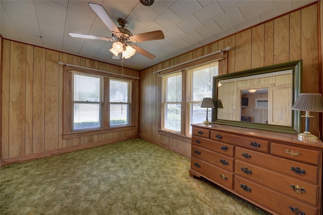 unfurnished bedroom with light carpet, baseboards, wood walls, and multiple windows
