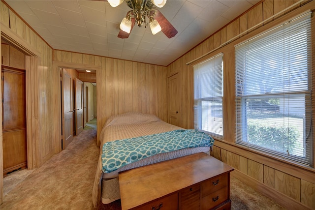 bedroom featuring wooden walls, ceiling fan, and light carpet