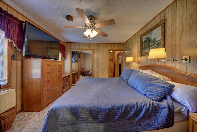 carpeted bedroom with ceiling fan, a textured ceiling, wooden walls, and a closet