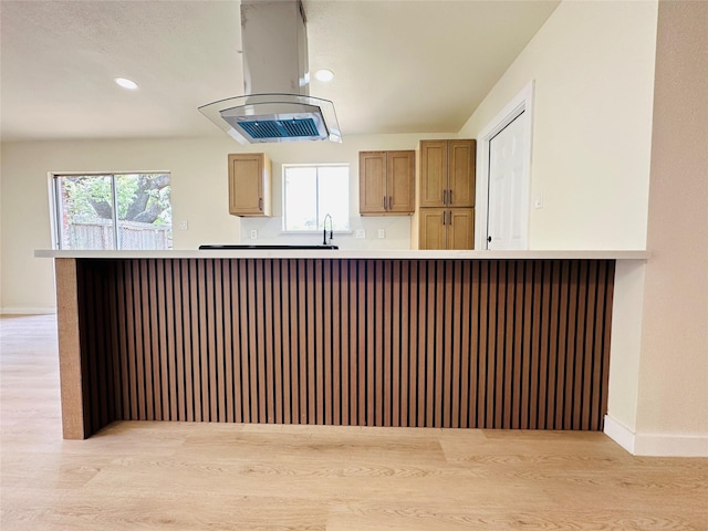 kitchen featuring island range hood, light wood finished floors, plenty of natural light, a sink, and recessed lighting