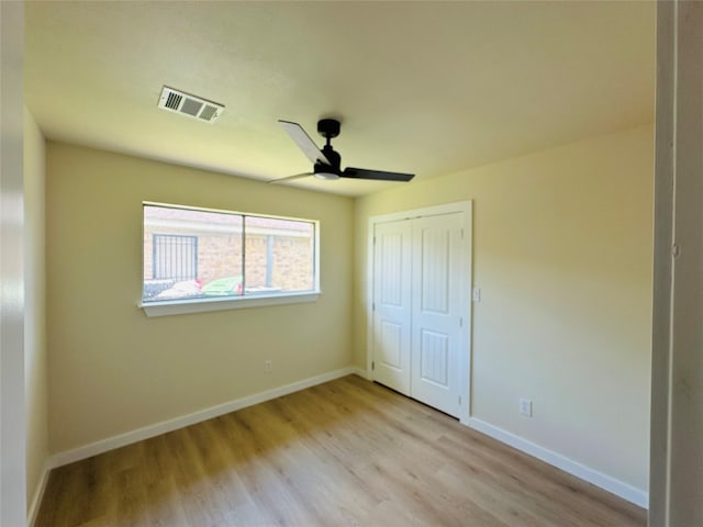 unfurnished bedroom featuring wood finished floors, a closet, baseboards, and a ceiling fan