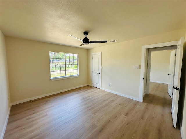 unfurnished bedroom featuring light wood finished floors, baseboards, a textured ceiling, and a ceiling fan