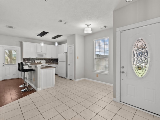 entryway with baseboards, visible vents, and light tile patterned floors
