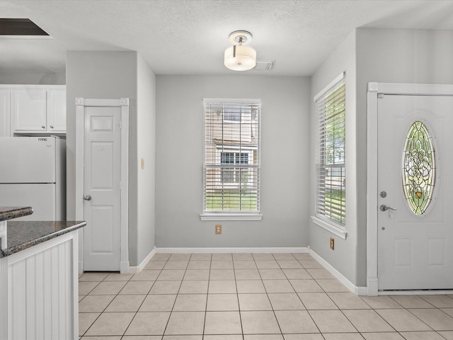 entrance foyer with baseboards, a healthy amount of sunlight, and light tile patterned floors