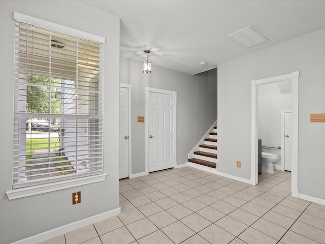 interior space featuring baseboards, stairs, and light tile patterned floors