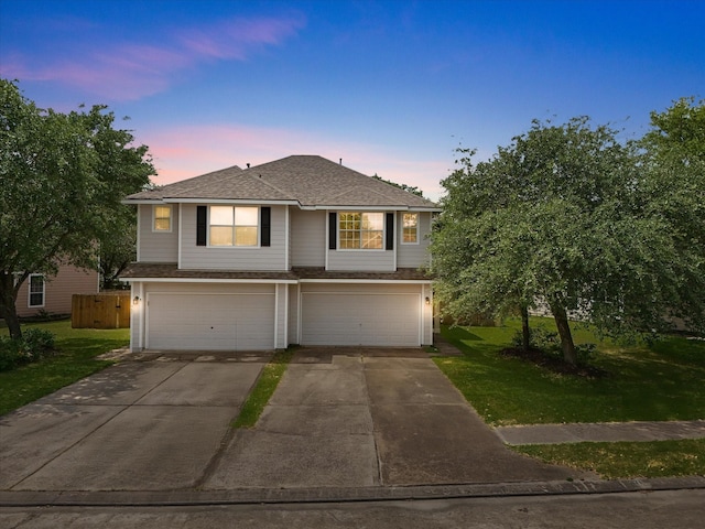 traditional-style home with concrete driveway, an attached garage, roof with shingles, and a front lawn
