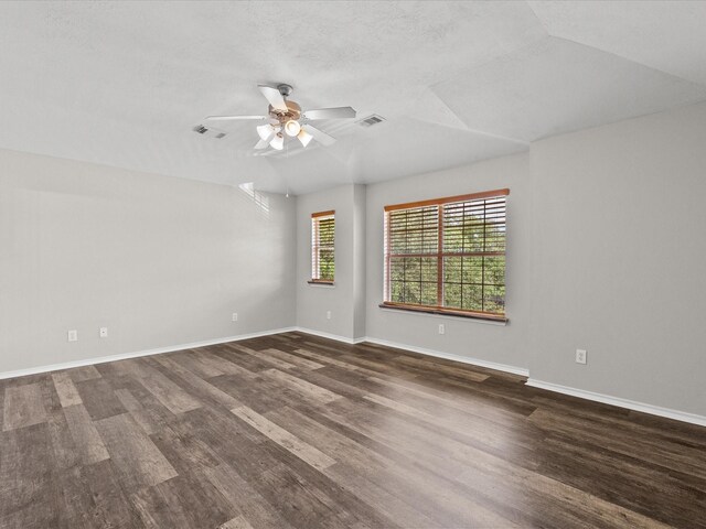 empty room with lofted ceiling, visible vents, dark wood-style flooring, baseboards, and ceiling fan