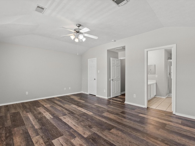unfurnished bedroom featuring ensuite bath, lofted ceiling, wood finished floors, and visible vents