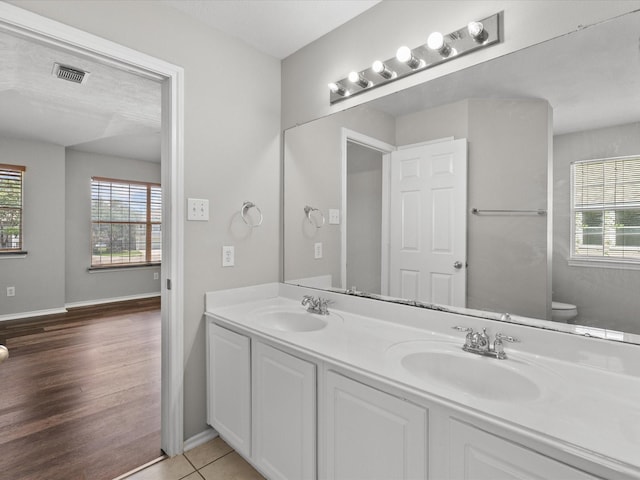 bathroom featuring wood finished floors, a sink, visible vents, and double vanity