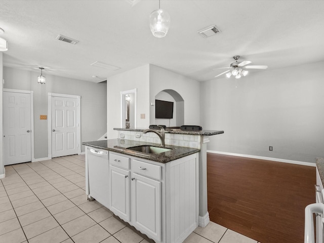 kitchen featuring dishwasher, visible vents, light tile patterned floors, and a sink
