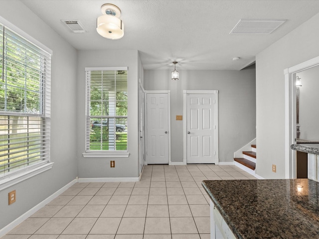 entryway with light tile patterned flooring, stairway, visible vents, and baseboards