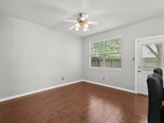 interior space with baseboards, a ceiling fan, and dark wood-style floors