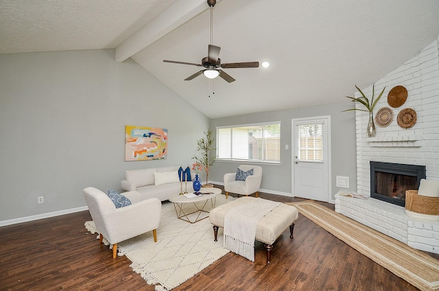 living area with wood finished floors, vaulted ceiling with beams, a ceiling fan, baseboards, and a fireplace