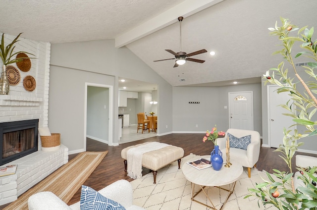 living area featuring wood finished floors, a brick fireplace, a ceiling fan, and lofted ceiling with beams