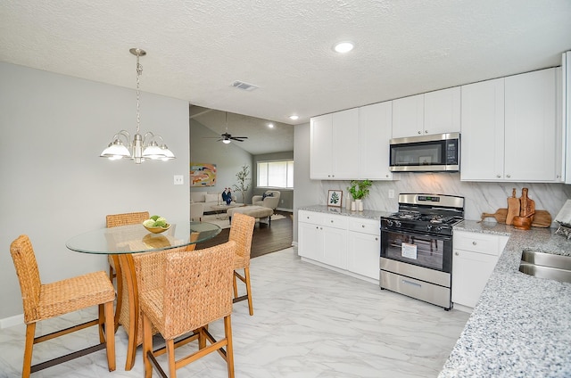kitchen featuring white cabinets, marble finish floor, visible vents, pendant lighting, and appliances with stainless steel finishes