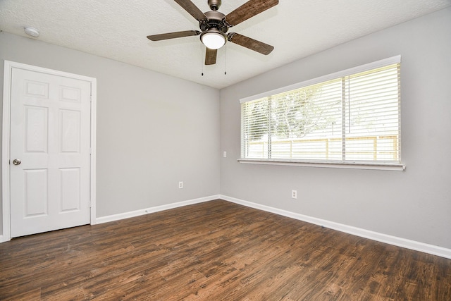 spare room featuring dark wood finished floors, baseboards, a ceiling fan, and a textured ceiling