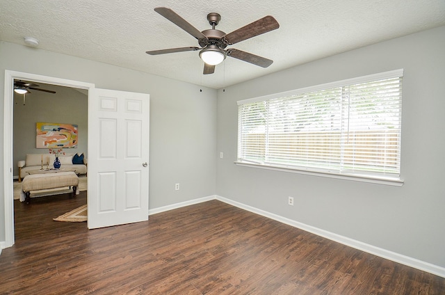 unfurnished bedroom featuring dark wood finished floors, a textured ceiling, a ceiling fan, and baseboards