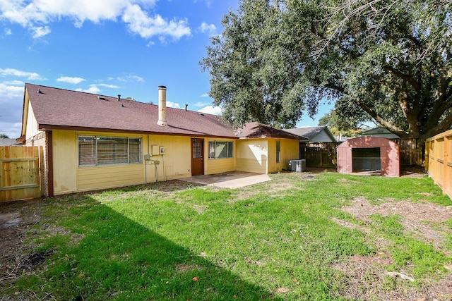 back of property with a storage shed, an outbuilding, a fenced backyard, a yard, and a patio