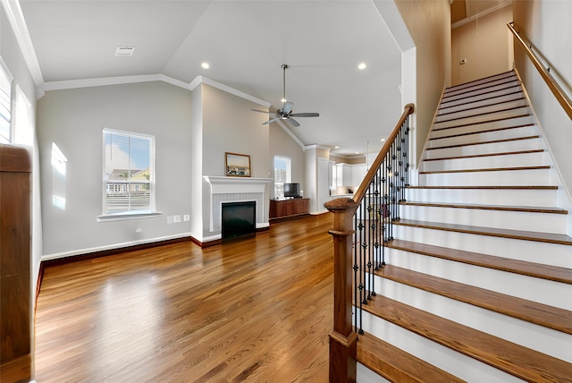 6 Compass Cir, Galveston, TX 77554 - stairs with ornamental molding, ceiling fan, a tiled fireplace, and wood finished floors