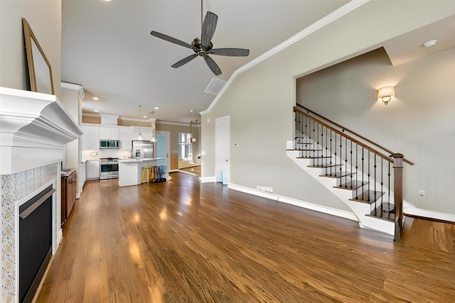 6 Compass Cir, Galveston, TX 77554 - unfurnished living room with crown molding, stairway, wood finished floors, a tiled fireplace, and a ceiling fan