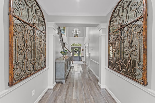 corridor featuring baseboards, ornamental molding, wood finished floors, and a notable chandelier