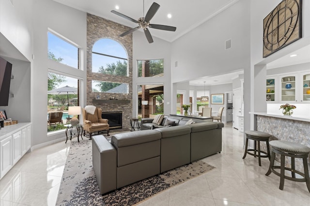 living area featuring a ceiling fan, a large fireplace, high vaulted ceiling, ornamental molding, and recessed lighting