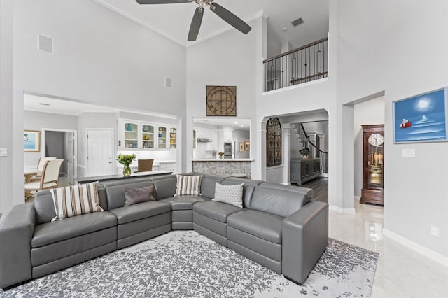 living area featuring crown molding, visible vents, baseboards, ceiling fan, and a high ceiling