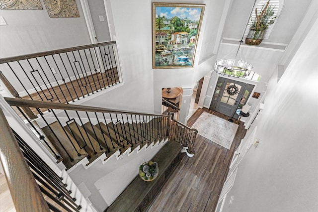 stairs with a high ceiling, a chandelier, and wood finished floors