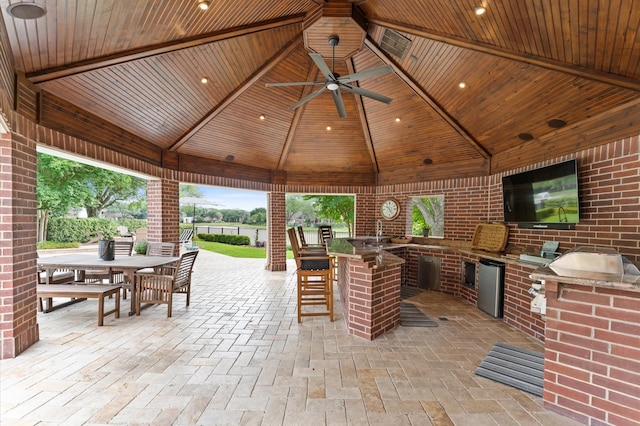 view of patio / terrace with outdoor wet bar, a gazebo, exterior kitchen, outdoor dining area, and a ceiling fan