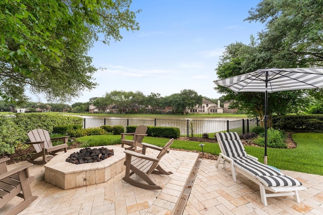 view of patio featuring a water view, a fire pit, and fence