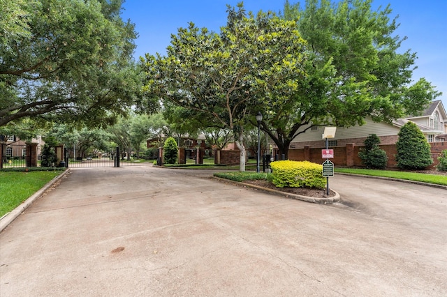 view of street featuring street lighting, curbs, a gated entry, and a gate