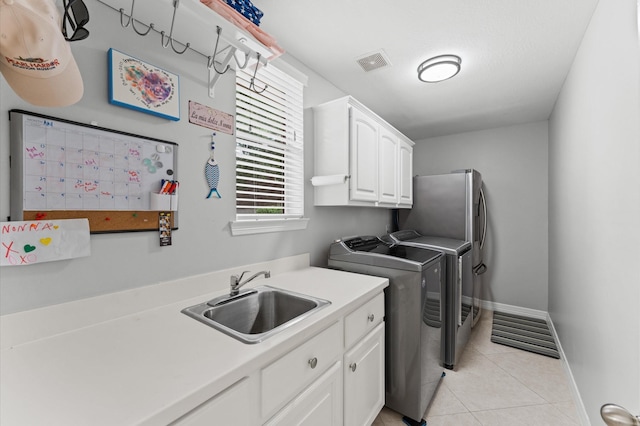 washroom with visible vents, washing machine and clothes dryer, cabinet space, a sink, and light tile patterned floors