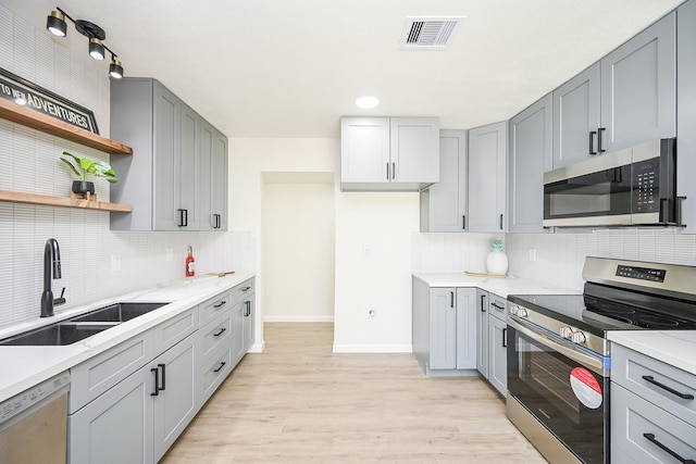 kitchen featuring open shelves, a sink, baseboards, appliances with stainless steel finishes, and visible vents