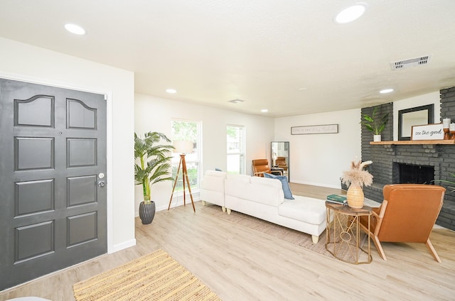 living area with a fireplace, wood finished floors, visible vents, and baseboards