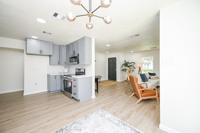 kitchen featuring baseboards, appliances with stainless steel finishes, gray cabinetry, and visible vents